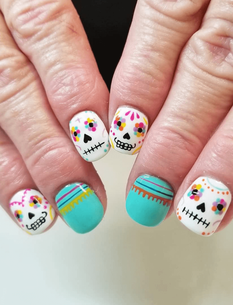 Sugar skull nail art with colorful polka dots on white background, and teal nails with pink and yellow stripes, inspired by Cinco de Mayo traditions.