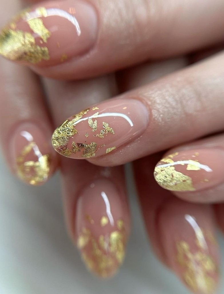 Wedding nails with a natural blush base embellished with scattered gold leaf flakes, creating a luxurious yet understated bridal manicure for a sophisticated wedding look.