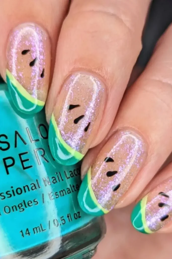 Hand with Watermelon Nail Designs featuring glittery nails with black seeds and green and yellow tips, resembling watermelon slices.