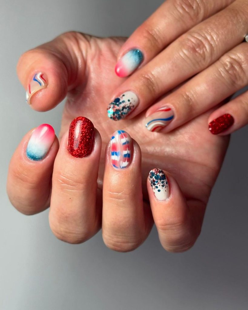 Hands showing 4th of July nail designs featuring acrylic nails with red, blue and white swirls, ombre nails and bold red glitters